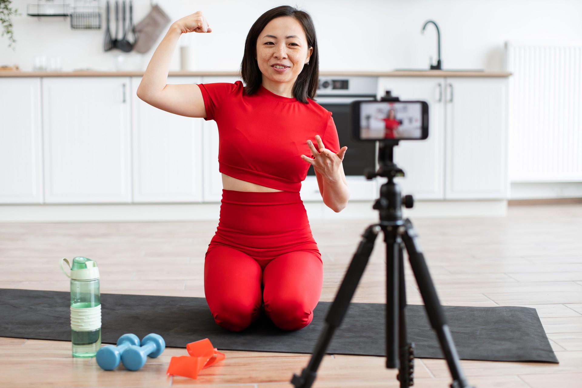 Woman filming fitness tutorial at home flexing arm muscle